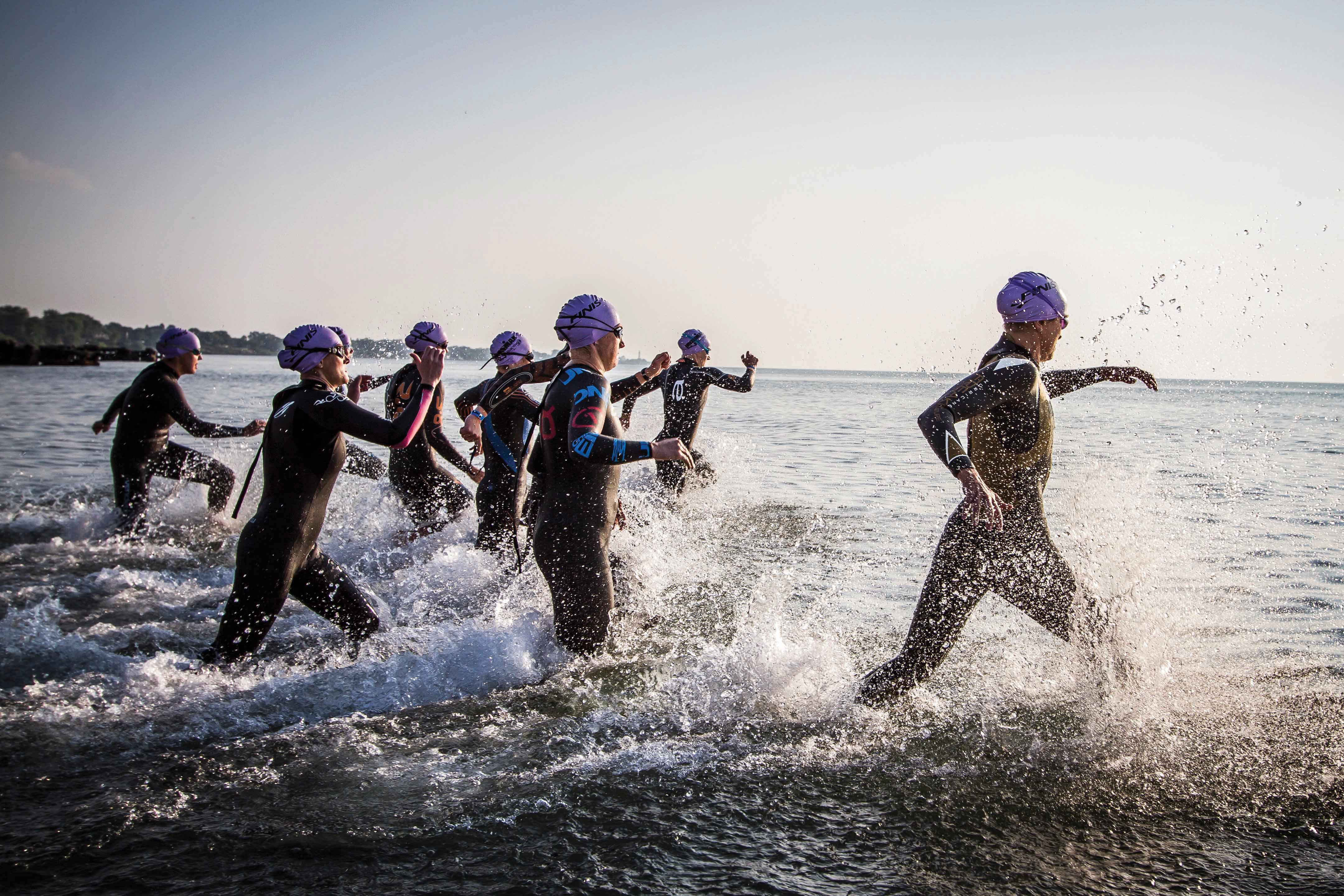 athletes running into body of water